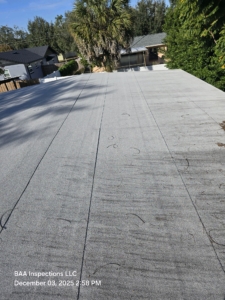 Flat modified bitumen roof surface with visible wear and debris.