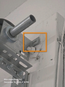 Improperly secured garage door track connection observed during a final new-construction inspection, presenting a potential safety concern.