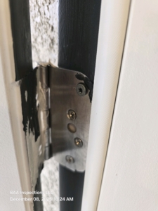 Door hinge improperly secured with missing or loose fasteners observed during a final new-construction inspection.